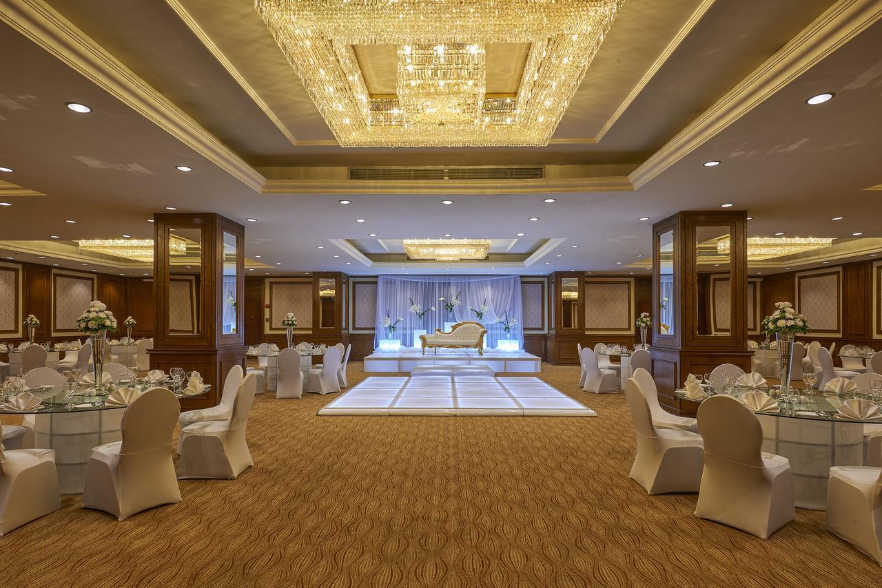 โรงแรมซาเฟอไคโร Giza ภายนอก รูปภาพ The photo shows an elegantly decorated event space. The room features a beautiful chandelier hanging from the ceiling, providing a warm glow. In the center, there is a raised platform that appears to be set up for a ceremony or celebration. Surroundi