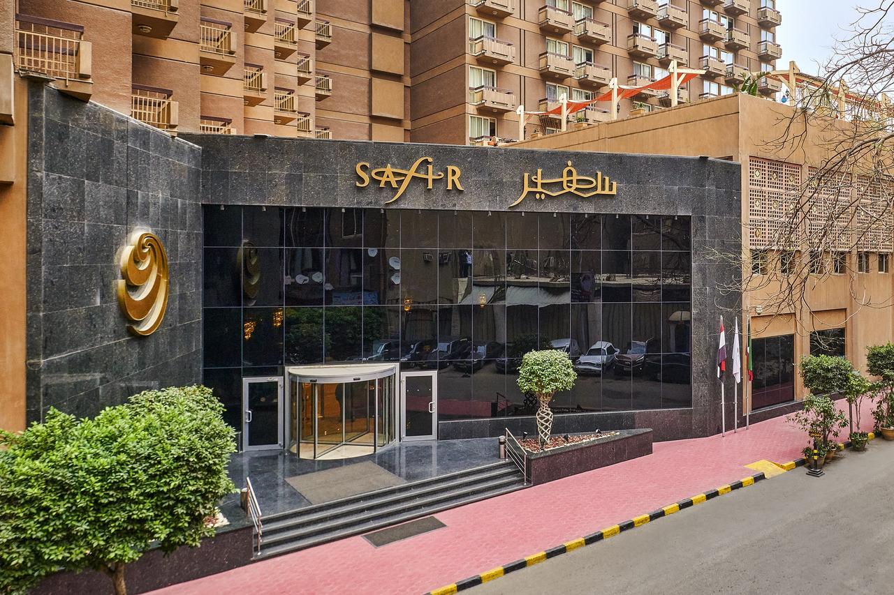 โรงแรมซาเฟอไคโร Giza ภายนอก รูปภาพ The photo depicts the entrance of a modern building, which appears to be a hotel or a commercial establishment. The facade features a large glass front with reflective surfaces. Above the entrance, there is a prominent sign displaying the name of the